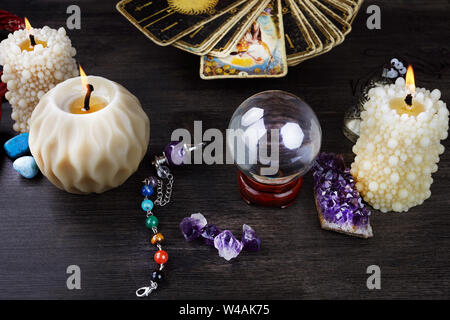 Still life with the tarot cards, magic stones and candles on wooden table. Fortune telling seance or magic ritual. Stock Photo