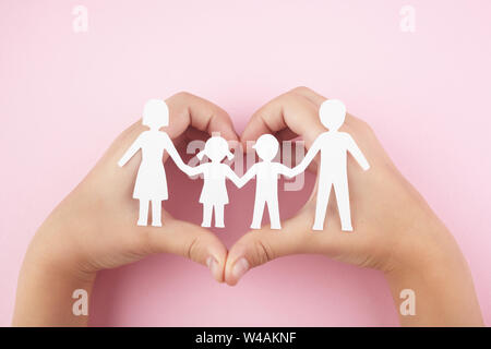 Paper family in child hands on pink background. Top view Stock Photo