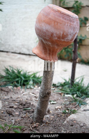 An old brown earthenware jug strung on the base of the fence, wattle, Ukrainian decor Stock Photo