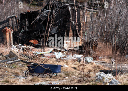 Blue baby carriage near old wooden abandoned burned-down house Stock Photo