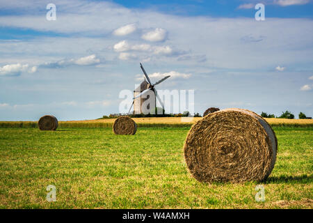 Moulin de Moidrey, historic Moidrey stone windmill with haystack and wheat field in the foreground, Pontorson, Normandy, France. Stock Photo