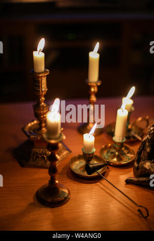 Burning candles in old brass candle holders Stock Photo