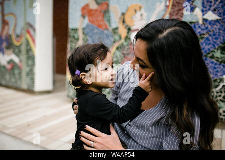 Mother & daughter looking at one another in front of mural Stock Photo