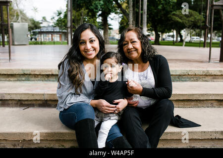 Three generations of women smiling for camera in park Stock Photo