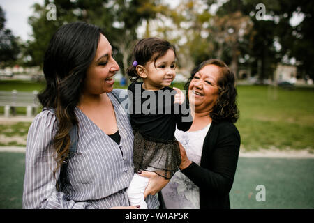 Mother holding daughter as grandmother looks on Stock Photo