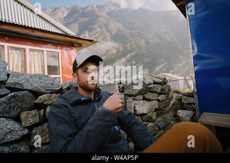 Young man sipping coffee in mountains Stock Photo