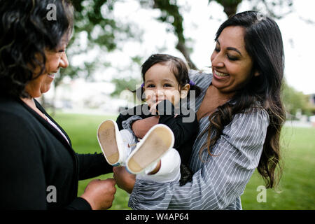 Grandmother, mother & daughter hugging and laughing in park Stock Photo
