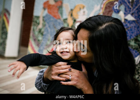 Mother kissing daughter in front of mural Stock Photo
