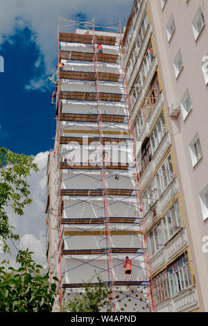 Scaffolding on a multistory building. Warming of the outer wall panel. A working man isolates the walls of a multistory building Stock Photo
