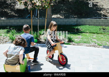 Kids outside play on wooden bicycles Stock Photo