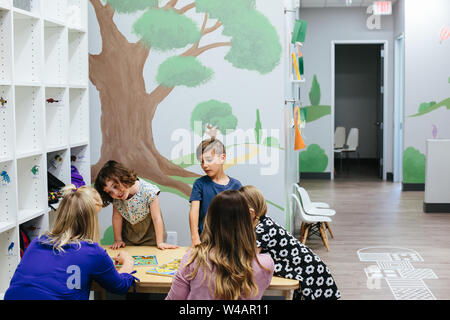 kids stand around a table with teachers and puzzles Stock Photo