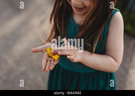 Mid-level view of little girl holding flower and smiling Stock Photo