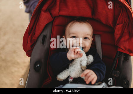 Smiling portrait of baby boy in stroller with pacifier Stock Photo