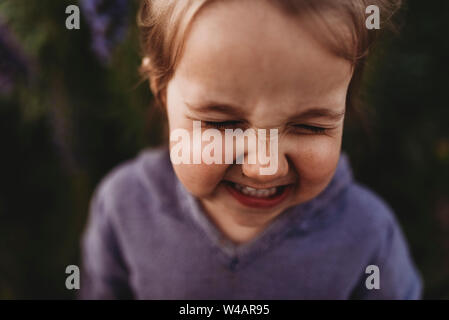 Close up portrait of little toddler girl scrunching nose and laughing