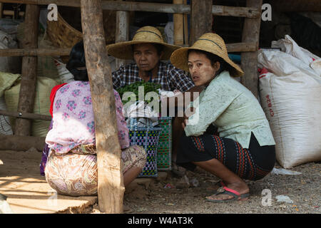 Indein, Myanmar - March 2019: Burmese women in straw hats having a chat at the street market on Inle lake, Myanmar Stock Photo