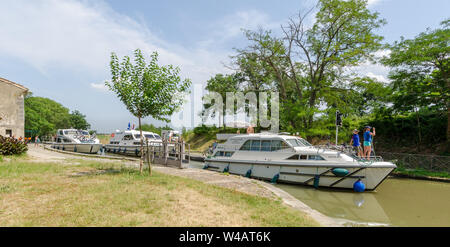 A lock on the Canal du Midi France on a summer's day with three pleasure motor boats preparing to leave it Stock Photo