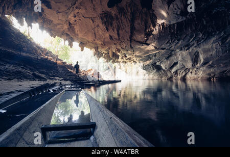 Human silhouette stands inside water cave with torch in hand in Konglor, Laos. Stock Photo
