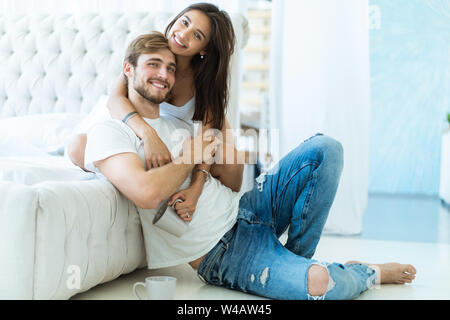Loving young couple hugging and relaxing on sofa at home. Stock Photo