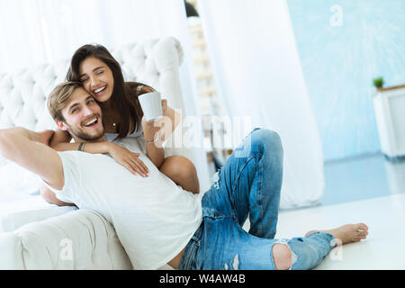 Loving young couple hugging and relaxing on sofa at home. Stock Photo