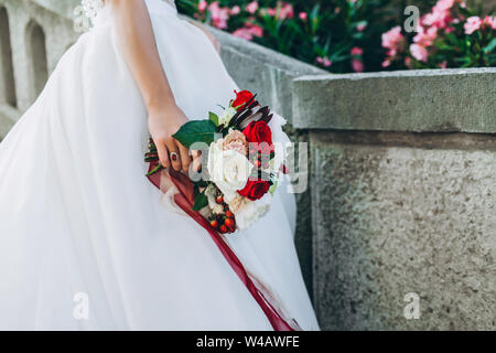 Wedding bouquet with bright flowers in bride's hand. Close up, no face seen. Stock Photo