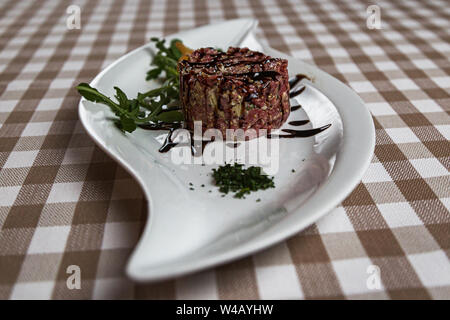The tartare is a dish of French origin made from beef or horse meat which is served raw and cut with a knife into very small pieces. served with green Stock Photo
