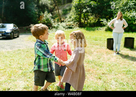 Portrait of three children holding hands and playing together Stock Photo