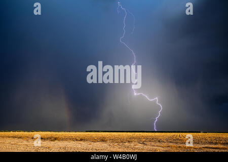 A  lightning bolt strikes through a microburst against a dark, stormy sky near Willcox, Arizona Stock Photo
