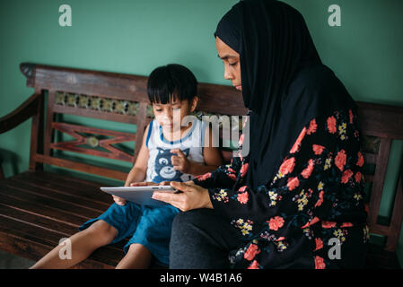 Asian mother and son playing games on smart tablet