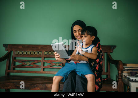 Asian mother and son making video call on smart tablet Stock Photo