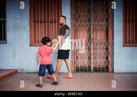 Asian man and son walking in front of shops Stock Photo