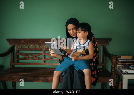 Asian woman with son playing tablet Stock Photo
