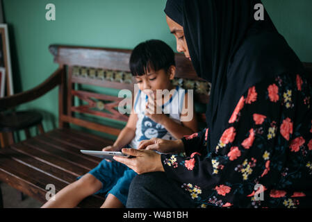 Asian mother and son playing games on smart tablet Stock Photo