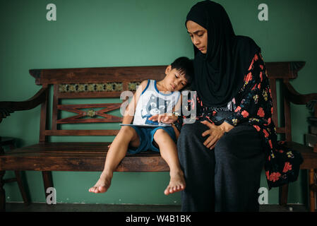 Asian woman with son playing games on smart tablet Stock Photo