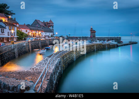 At dusk the streetlights flicker on in the picturesque little North Devon harbour of Lynmouth as the incoming tide causes the small boats pitch and ro Stock Photo