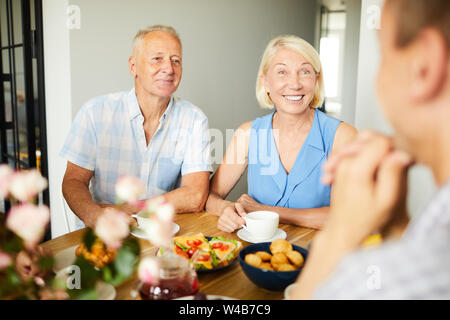 Portrait of smiling mature couple sitting at dinner table with friends and family, copy space Stock Photo