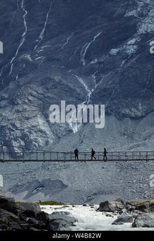 Hikers on Hooker River Footbridge & Mt Sefton, Aoraki / Mt Cook National Park, Canterbury, South Island, New Zealand Stock Photo