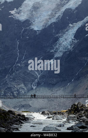 Hikers on Hooker River Footbridge & Mt Sefton, Aoraki / Mt Cook National Park, Canterbury, South Island, New Zealand Stock Photo