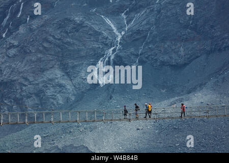 Hikers on Hooker River Footbridge & Mt Sefton, Aoraki / Mt Cook National Park, Canterbury, South Island, New Zealand Stock Photo