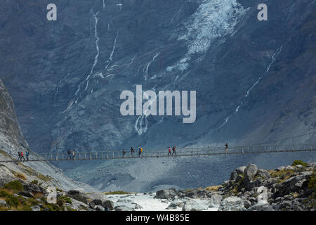 Hikers on Hooker River Footbridge & Mt Sefton, Aoraki / Mt Cook National Park, Canterbury, South Island, New Zealand Stock Photo