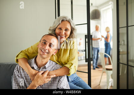 Portrait of happy mature couple posing sitting on sofa at home, copy space Stock Photo