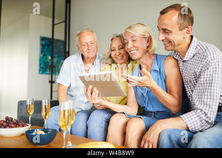 Group of contemporary adult people using digital tablet sitting on sofa at home, copy space Stock Photo