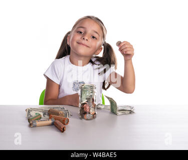Girl playing and counting money from her glass piggy bank with copy space. Concept for business or teaching children for saving money. Stock Photo