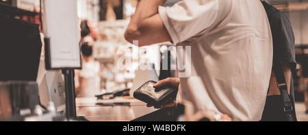 adult consumer paying with credit card in the store, holding a wallet s Stock Photo