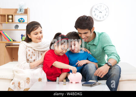 Parents assisting their children to save money Stock Photo