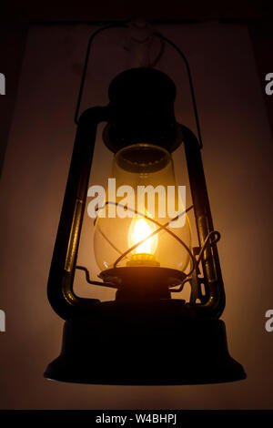 Old kerosene lamp hanging on the wall. Stock Photo