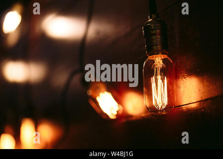 Vintage incandescent Edison type bulbs on wooden wall. Stock Photo