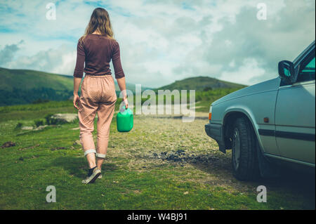 A young woman with a broken down car in nature is off looking for a gas station Stock Photo