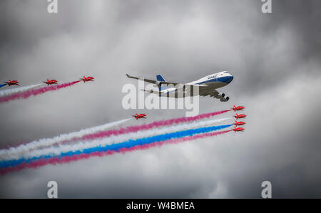 Flypast by the RAF Red Arrows aerobatic display team in formation with a BOAC liveried Boeing 747 at The Royal International Air Tattoo, Fairford, UK Stock Photo