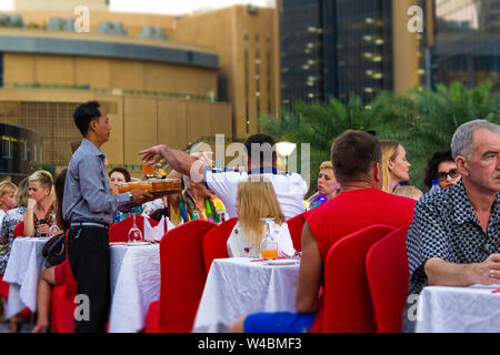 Dubai, UAE - November 29, 2018: Dinner for a group of tourists on the open deck of a cruise ship in Dubai Marina. Stock Photo