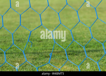 Torn football goal net close up. Old torn net on the football goal. Stock Photo